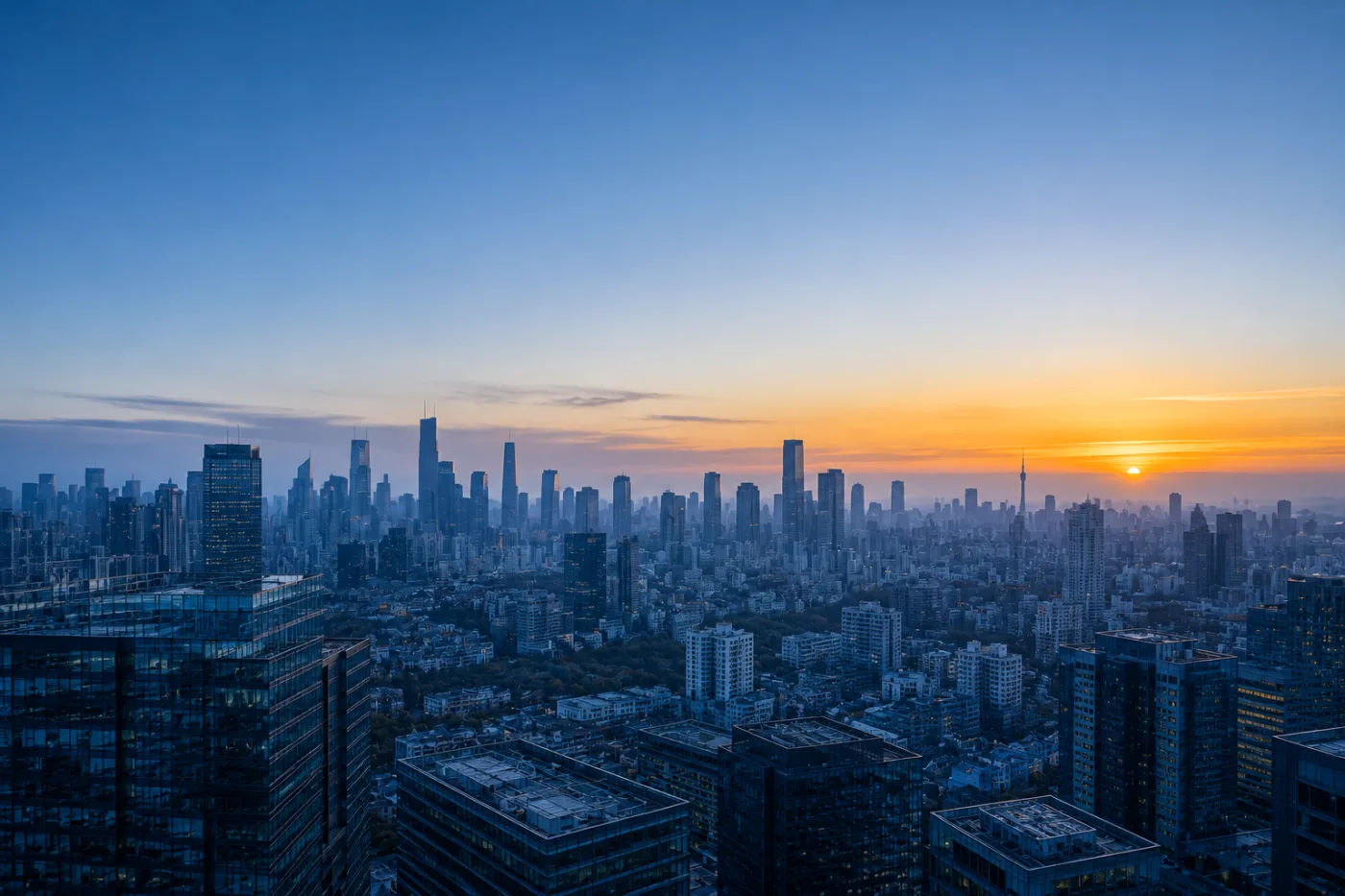 A city skyline at sunrise seen from above, the sun breaking the horizon